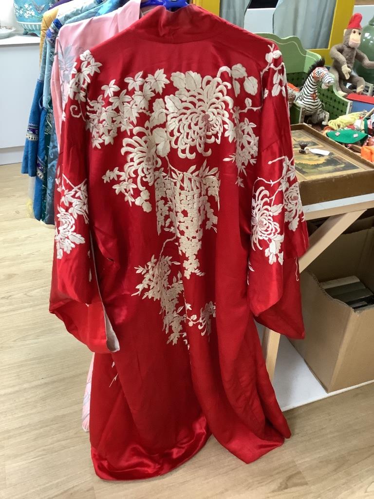 A pink silk Japanese kimono embroidered with wisteria and irises and butterflies, length 140cm, together with a red kimono embroidered with white wisteria and carnations